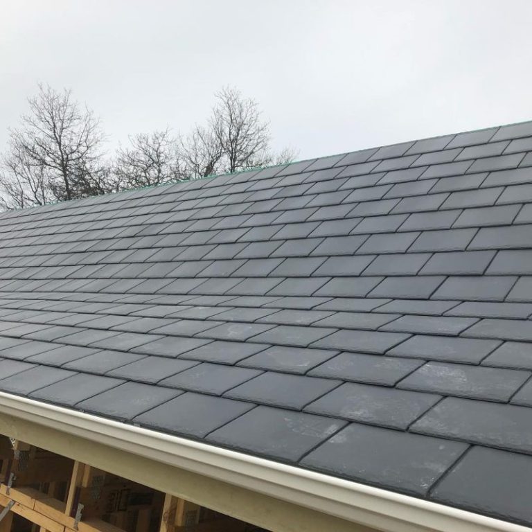 Close-up of a residential roof featuring high-quality, dark grey slate tiles installed with precise alignment.